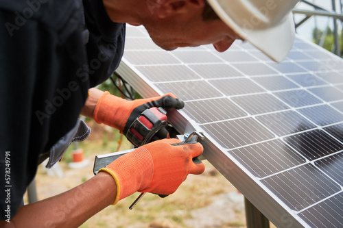 Workers installing solar panel on metal beams. Renewable and ecological energy. Cropped image of european men wearing workwear and helmets