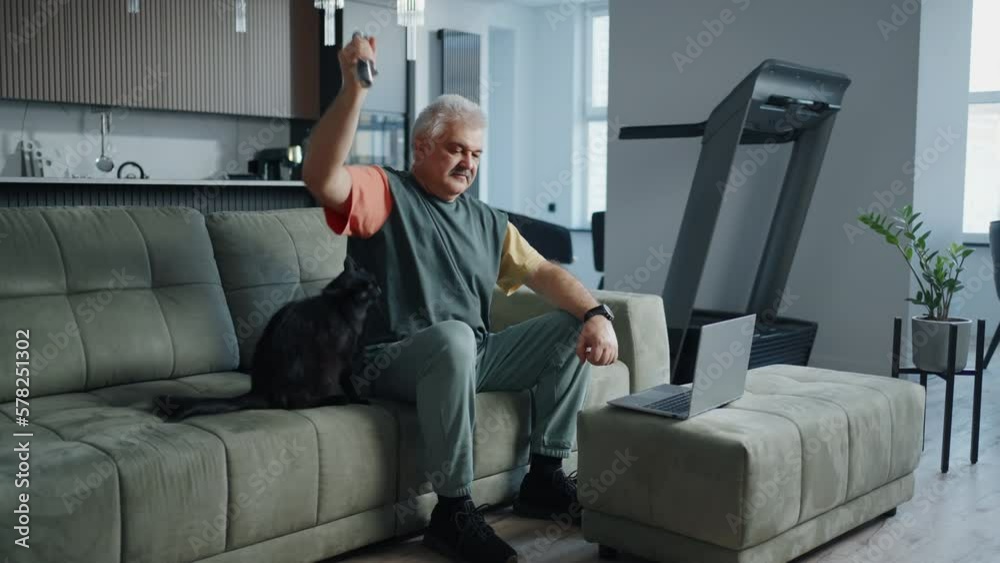 Home Fitness In Old Age, Senior Man Watching Online Workout And Doing Exercise With Dumbbells Home Fitness In Old Age, Senior Man Watching Online Workout And Doing Exercise With Dumbbells