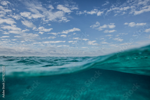 A split level shot of turquoise ocean water and clouds in a blue sky photo