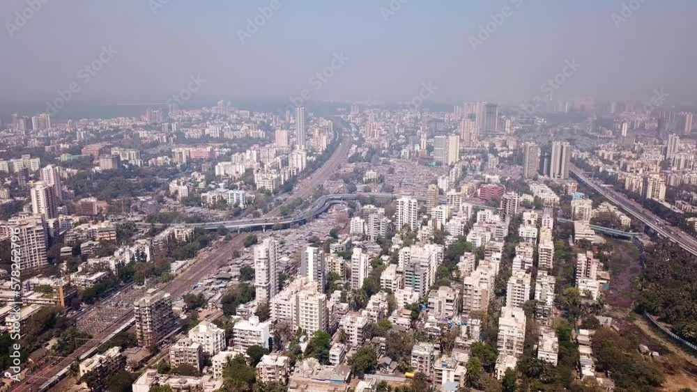 A hazy cityscape of Mumbai from above with bustling metropolitan city with its skyscrapers, traffic, and bustling downtown. The aerial footage shows Bombay's busy roads and highways with skyline. A hazy cityscape of Mumbai from above with bustling metropolitan city with its skyscrapers, traffic, and bustling downtown. The aerial footage shows Bombay's busy roads and highways with skyline.