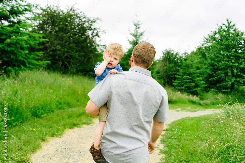 Rear view of a father carrying his sleepy toddler down a path Rear view of a father carrying his sleepy toddler down a path