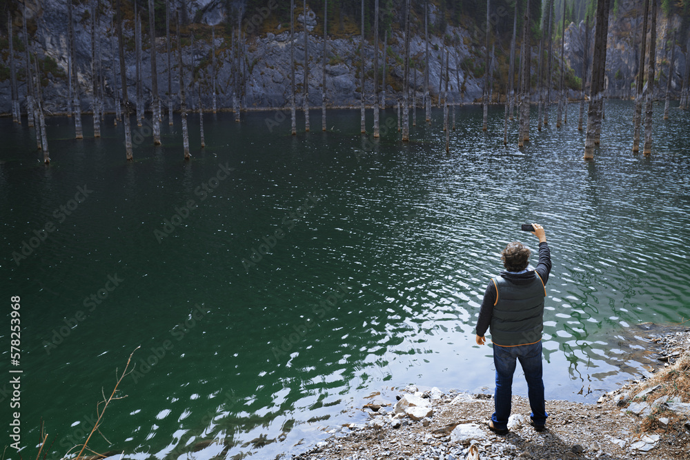 Man taking picture with smartphone at the Mountain lake Man taking picture with smartphone at the Mountain lake