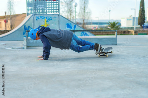 Rear view of young skater performing a trick on ground at skate park photo