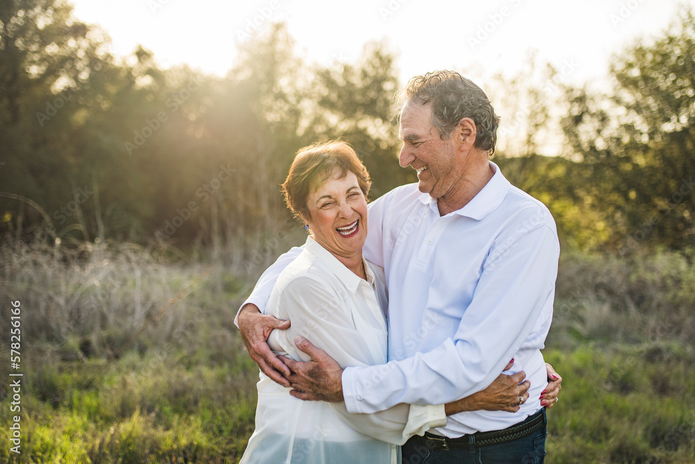 Senior couple hugging and laughing outside in backlight Senior couple hugging and laughing outside in backlight