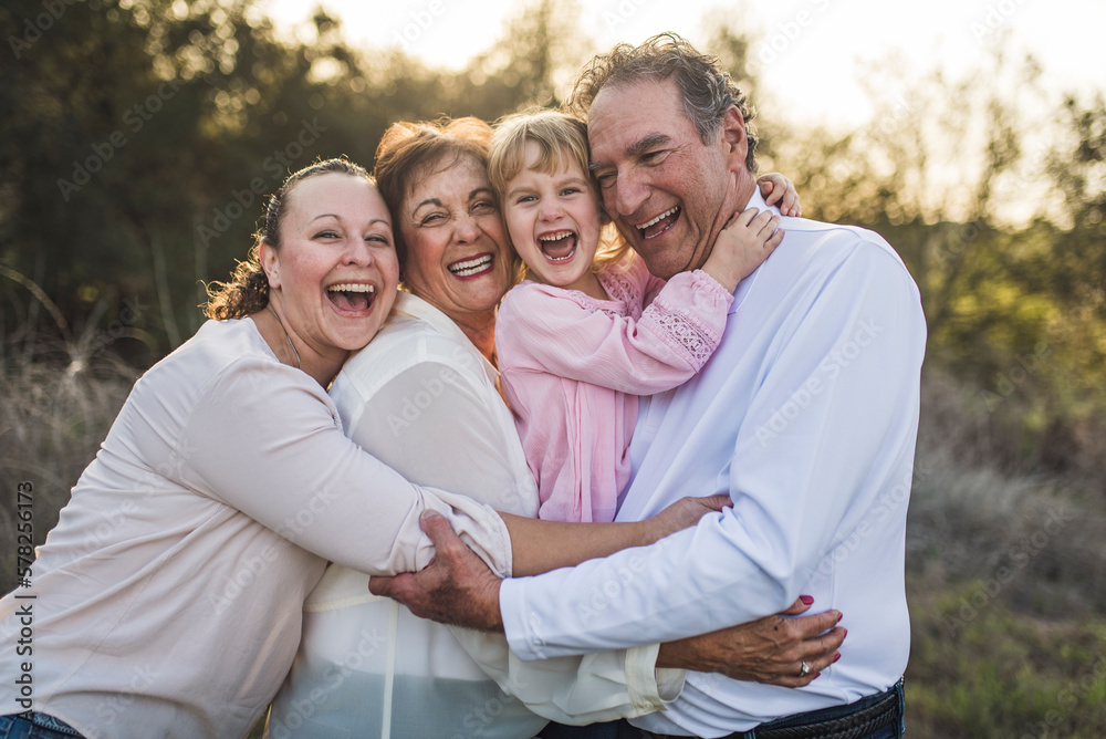 Multigenerational family embracing and laughing in field Multigenerational family embracing and laughing in field