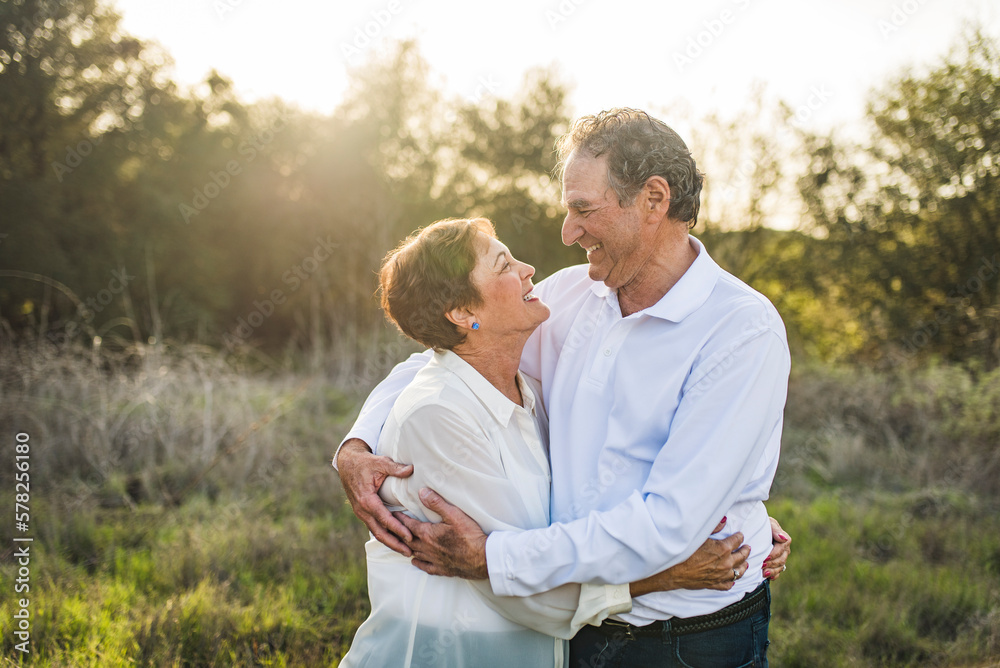 Senior couple hugging and looking at each other outside in backlight Senior couple hugging and looking at each other outside in backlight