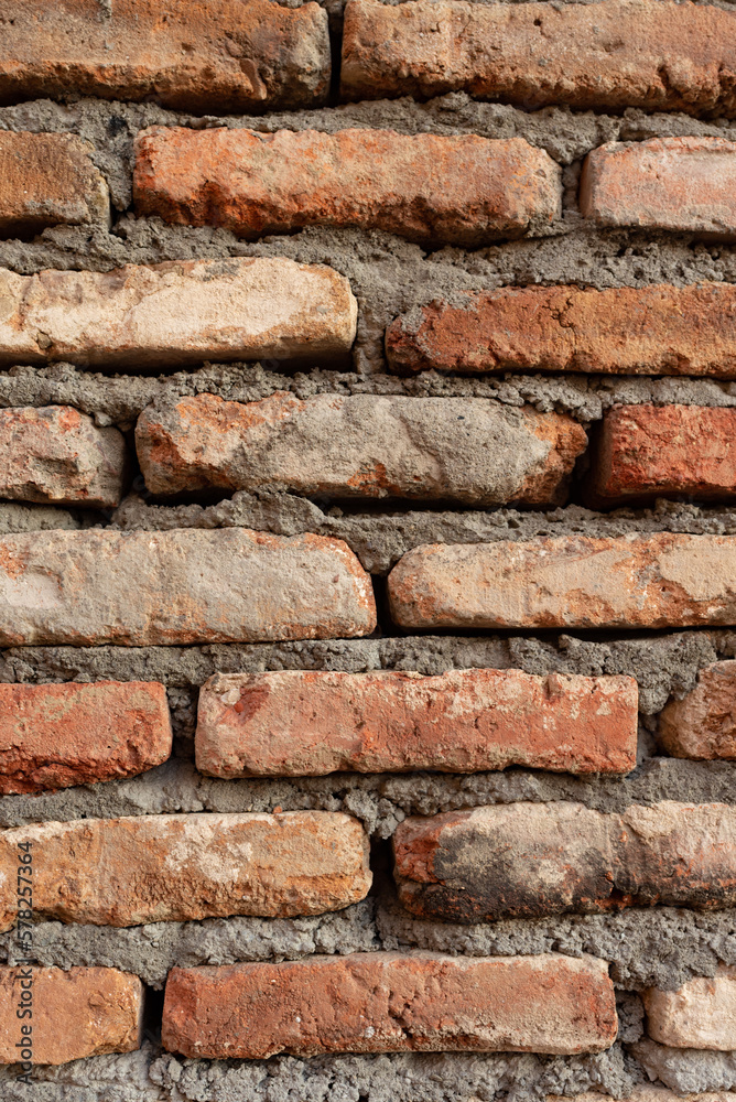Texture of old brickwork with holes. Dark red brick wall in the old city. Vertical photo close up Texture of old brickwork with holes. Dark red brick wall in the old city. Vertical photo close up