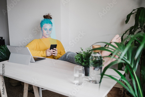 Freelancer using smart phone sitting in home office photo