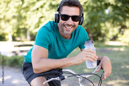 man on bicycle wearing headphones and holding bottle of water © auremar