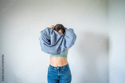 Woman getting dressed in front of wall photo