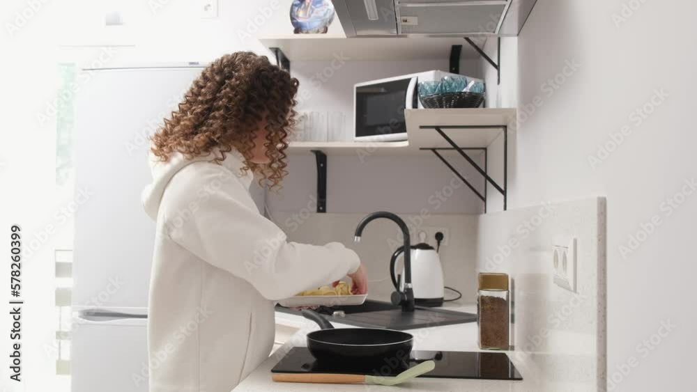 Cute woman at home cooking and enjoying cooking in a trendy home kitchen. Healthy eating and lifestyle, vegan family and recipe concept Cute woman at home cooking and enjoying cooking in a trendy home kitchen. Healthy eating and lifestyle, vegan family and recipe concept