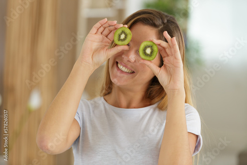 woman with kiwi slices in front of her eyes photo