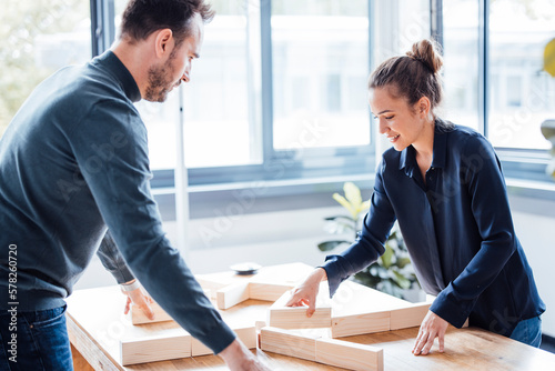Smiling businesswoman with businessman arranging wooden blocks in office