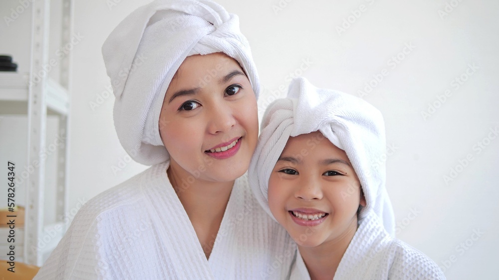 Smiling Asian mother and daughter wearing towels on head after shower and looking at camera. Bathtime concept Smiling Asian mother and daughter wearing towels on head after shower and looking at camera. Bathtime concept