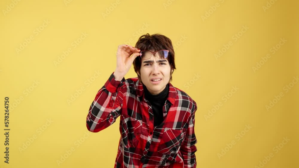 Androgynous person taking off her glasses to look ahead Androgynous person taking off her glasses to look ahead