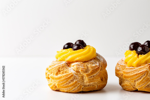 Italian dessert Zeppole di San Giuseppe, zeppola - baked puffs made from choux pastry, filled and decorated with custard cream and cherry. photo