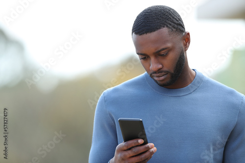 Sad black man reading chat on phone