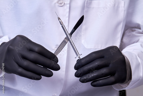 Doctor surgeon holds a scalpel with syringe. Surgical concept instrument.