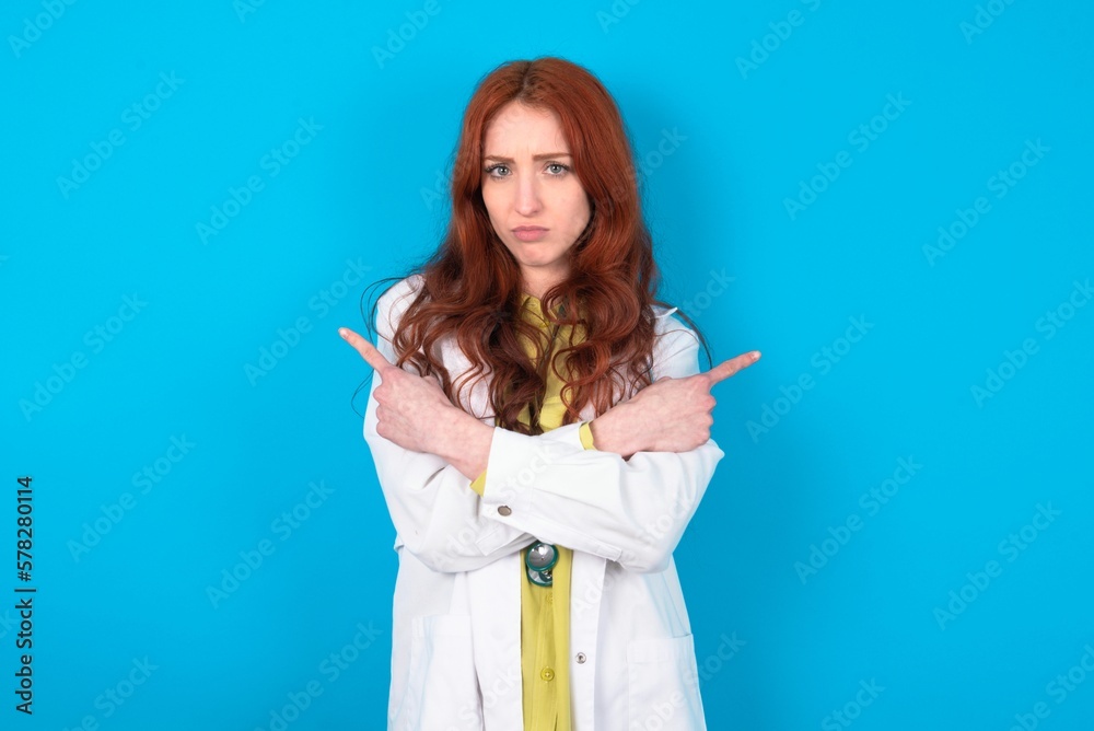Serious young doctor woman wearing medical uniform over blue background ...