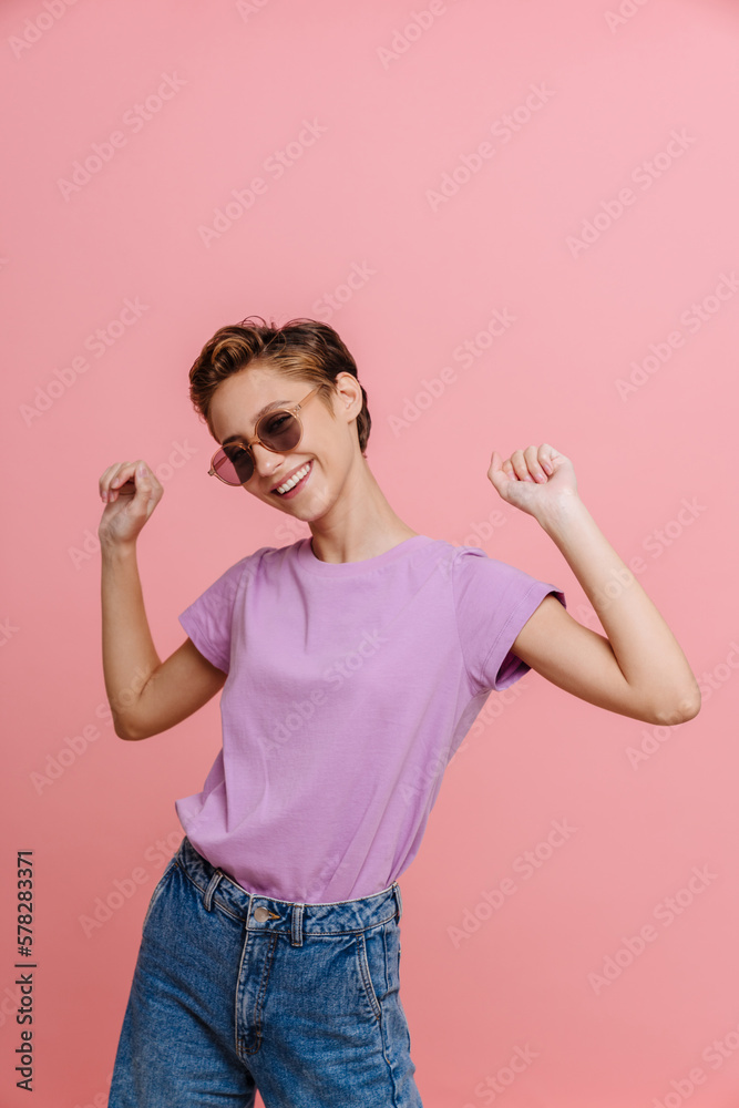 Young short-haired beautiful smiling woman in sun glasses dancing Young short-haired beautiful smiling woman in sun glasses dancing