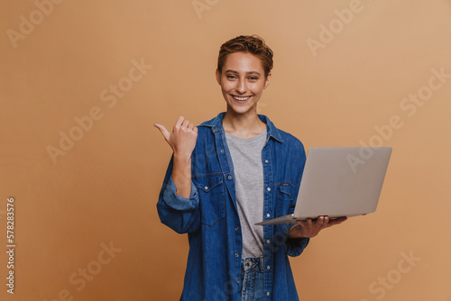 Portrait of young short-haired beautiful smiling woman holding laptop