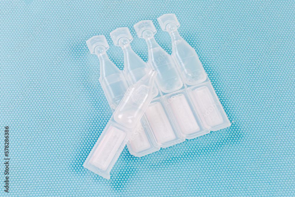 Eye drops in small disposable plastic ampoules, one open ampoule - obrazy, fototapety, plakaty 