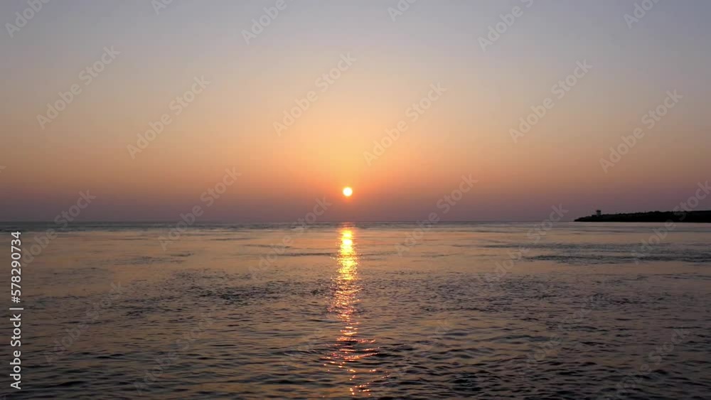 Vídeo com o sol a por-se no horizonte com o reflexo do sol sobre o mar em movimento rápido