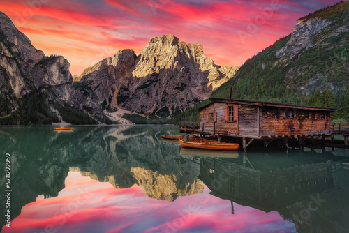 Fotobehang Colorful sunrise scene of beautiful Pragser Wildsee with wooden boats, reflectio