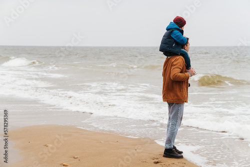 Father carrying on shoulders his son while enjoying sea view