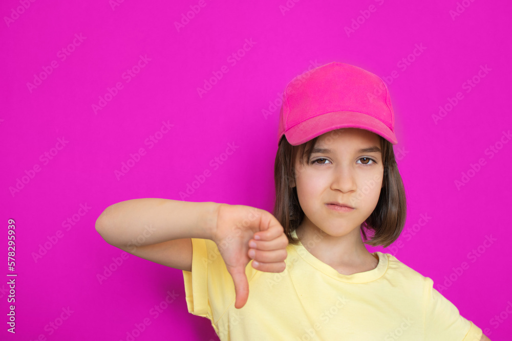 Close-up portrait of upset displeased cute little toddler girl showing thumb down over pink magenta background with copy space. Close-up portrait of upset displeased cute little toddler girl showing thumb down over pink magenta background with copy space.
