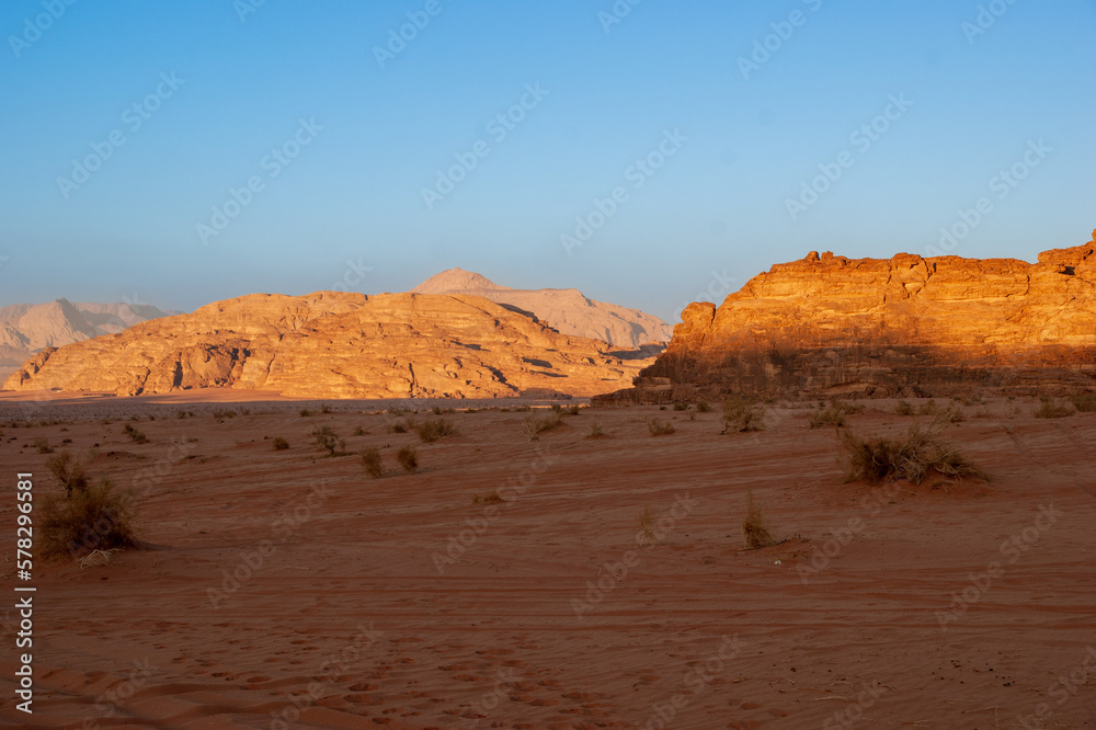 Jordan. Desert of Wadi Rum. Bizarre shapes of rocks in deserted desert. Landscape is similar to Martian landscapes. Sand is of beautiful pink color in rays of setting sun. Nature concept for design. Jordan. Desert of Wadi Rum. Bizarre shapes of rocks in deserted desert. Landscape is similar to Martian landscapes. Sand is of beautiful pink color in rays of setting sun. Nature concept for design.