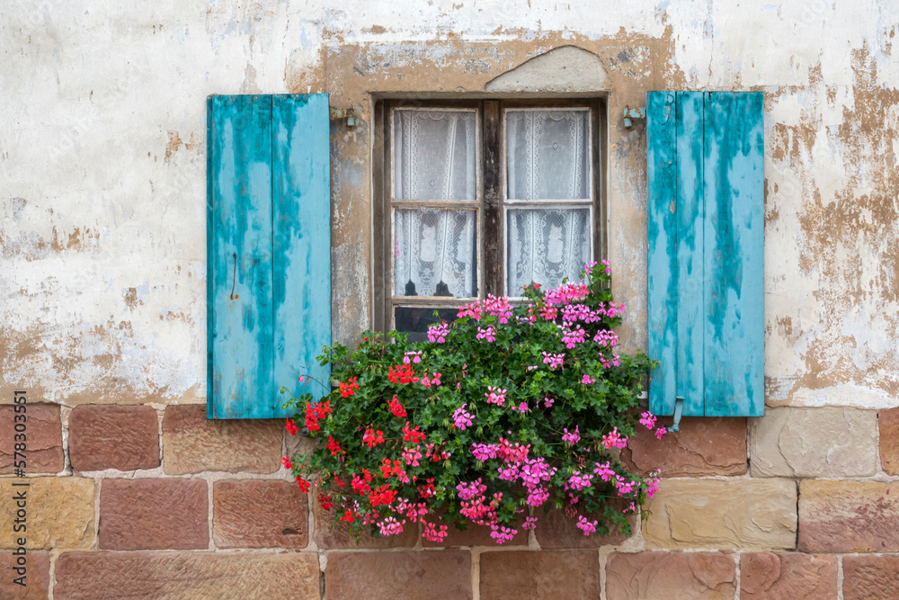 Altes Fenster mit blauen Fensterläden und Blumenschmuck