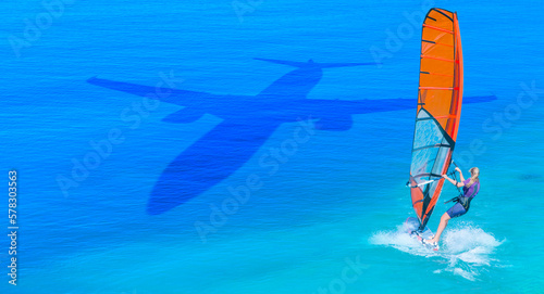 Travel concept - An passenger airplane shadow flying towards a tropical beach - Windsurfer surfing the wind on waves in Alacati - Cesme, Turkey 