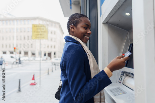 Young african woman withdrawing cash at the ATM photo