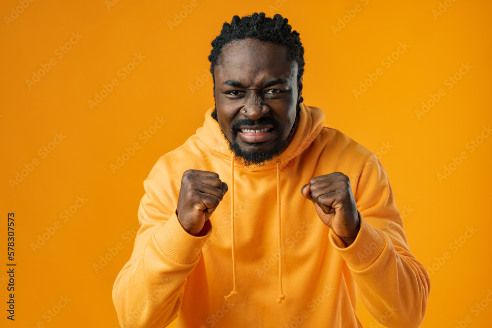 Portrait of excited african guy celebrating success with clenched fists against yellow background Portrait of excited african guy celebrating success with clenched fists against yellow background