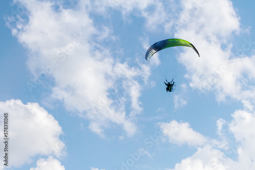 One paraglider is flying in the blue sky against the background of clouds.