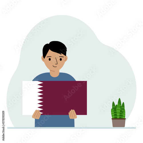 A little boy is holding the flag of Qatar in his hands. The concept of demonstration, national holiday or patriotism. Nationality.