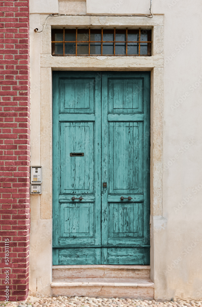 Old scratched turquoise wooden entrance door of a historic building