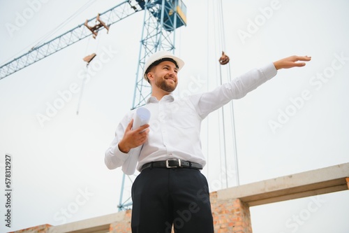 Architect at a construction site with blueprints
