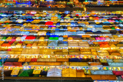 Close-up of rows of colorful market tents and food stalls at night.  © NPershaj