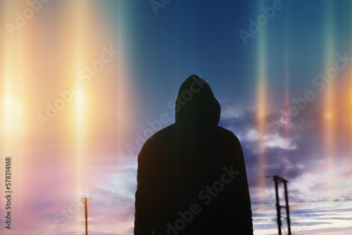 A mystical, science fiction concept of a man looking up at mysterious glowing UFO lights in the sky