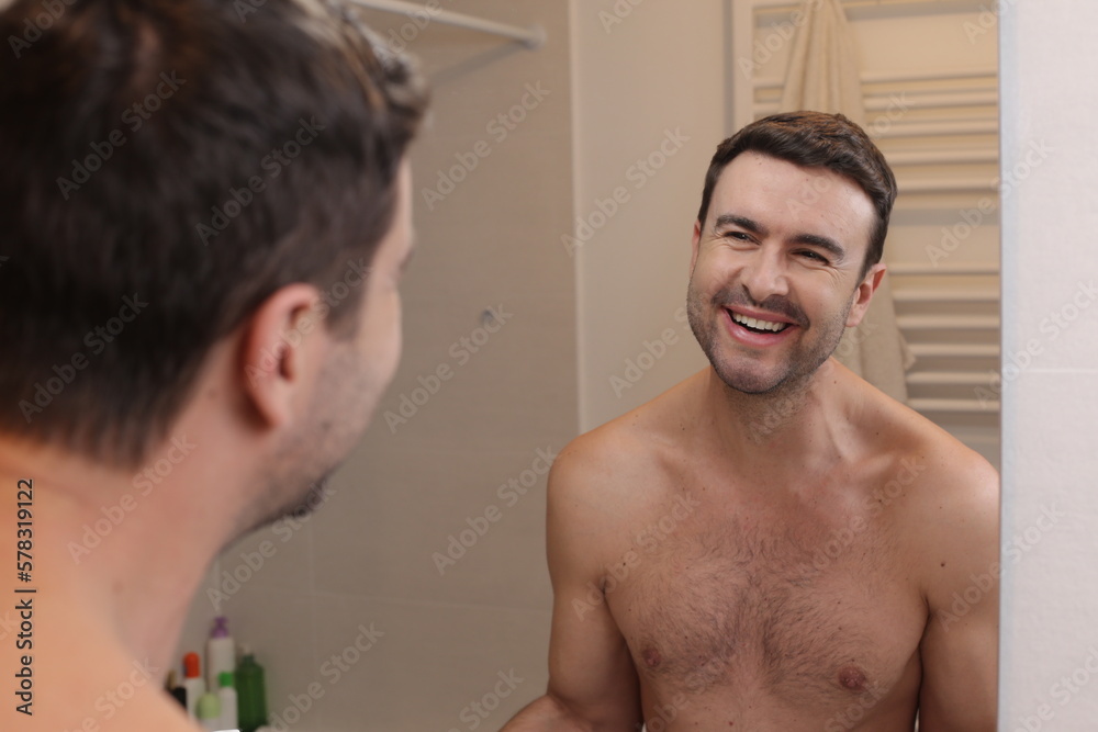 Cute shirtless man looking at his reflection in the bathroom Cute shirtless man looking at his reflection in the bathroom