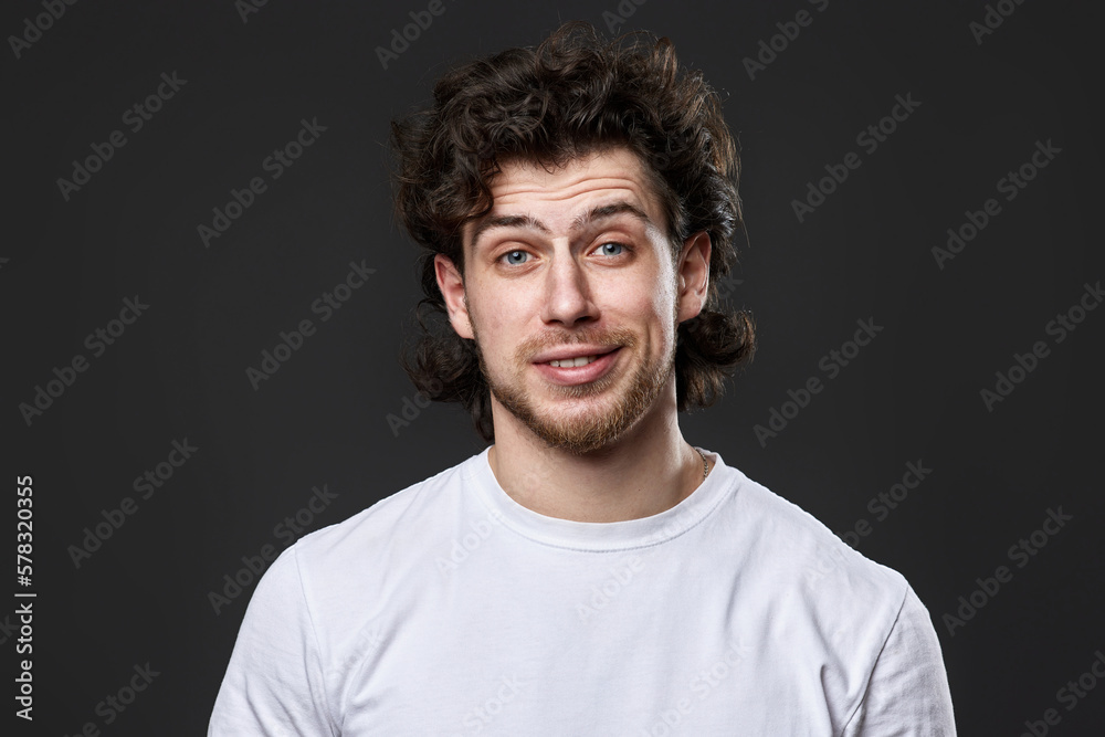 skeptic and nervous man in white t-shirt on dark gray background skeptic and nervous man in white t-shirt on dark gray background