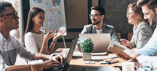 Happy business team working together while sitting at the desk in office