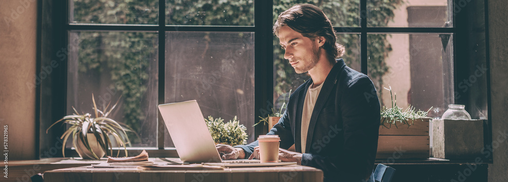 Confident young man in smart casual wear using laptop while sitting at ...