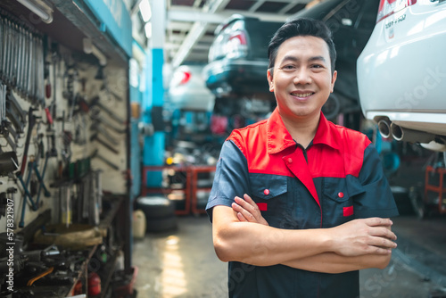 Asian automotive senior engineer people work in mechanics garage.Auto mechanic in uniform is looking at camera and smiling examining car...