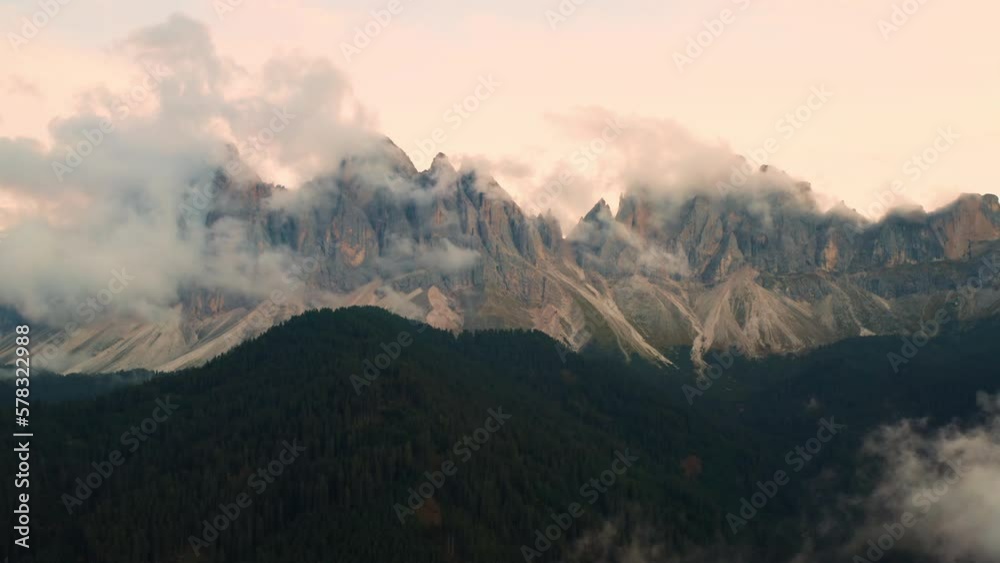 Cinematic view of Dolomites Alps covers by clouds at sunset in Val di Funes valley. Cinematic view of Dolomites Alps covers by clouds at sunset in Val di Funes valley.
