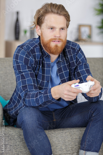 male gamer using controlpad from the sofa photo