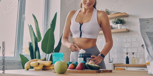 Close-up of sporty woman preparing protein cocktail in the kitchen