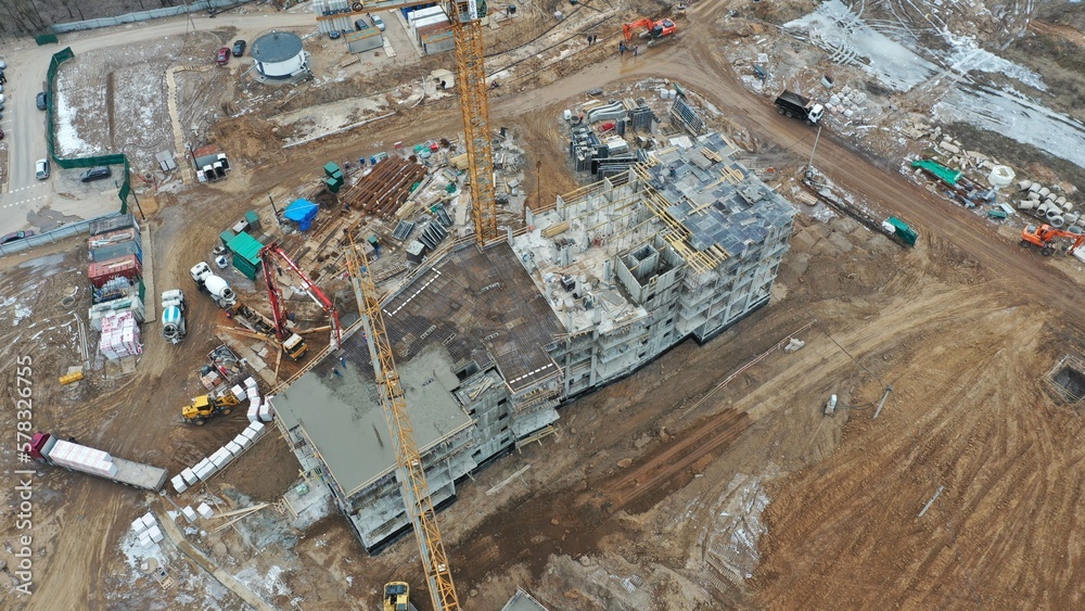 Bird's eye view of a construction site in spring (autumn) of a multi-storey residential complex for the sale of apartments. Construction of the concrete frame of the building. Construction equipment.